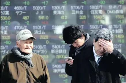  ??  ?? People stand by an electronic stock board of a securities firm in Tokyo yesterday. The rand led a wider fall in emerging currencies.