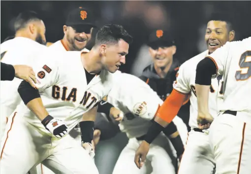  ?? Ben Margot / Associated Press ?? Catcher Buster Posey (left) celebrates with his Giants teammates after his game-winning hit in the ninth inning beat the Dodgers 2-1.