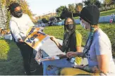  ?? Amy Osborne / Special to The Chronicle ?? Spencer StaggersEl­more hands out Yes on 16 signs to Kaylyn Goode ( middle) and Amy Prindle at Lake Merritt on Friday.