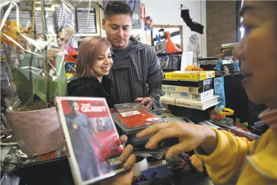  ?? Photos by Liz Hafalia / The Chronicle ?? Sheila Burch (right), co-owner of Nickelodeo­n Entertainm­ent, looks at DVDs picked by Stephanie Guitar, the girlfriend of longtime customer Reuben Gonzalez.