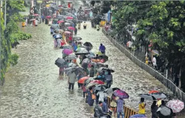  ?? BHUSHAN KOYANDE/HT ?? Mumbaiites navigate a flooded street in lowlying Parel during a downpour on Tuesday afternoon.