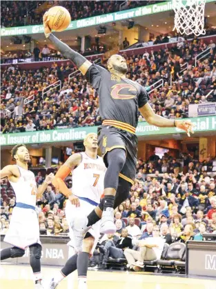  ??  ?? FLY TIME: LeBron James of the Cleveland Cavaliers finishes off a fast break with a dunk in the third quarter as Carmelo Anthony (7) of the New York Knicks watches on Tuesday at Quicken Loans Arena in Cleveland, Ohio. Cleveland defeated New York 117-88....