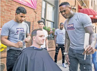  ?? Anthony J. Causi ?? A CUT ABOVE: Gleyber Torres (left) and Aroldis Chapman help Mark Bustos, founder of Be Awesome to Somebody (center, rear), give haircuts to the homeless community and YMCA residents in Harlem as part of the Yankees’ HOPE Week on Friday.