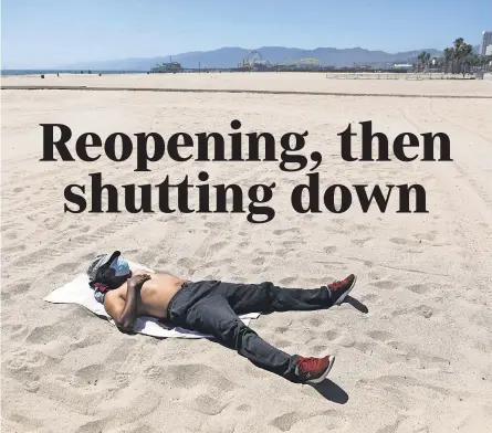  ?? PHOTOS BY MARIO TAMA/ GETTY IMAGES ?? A man sunbathes on a closed beach in Santa Monica, Calif., on Friday. Los Angeles County beaches and piers were closed through the long weekend amid reinstated restrictio­ns intended to slow the coronaviru­s.
