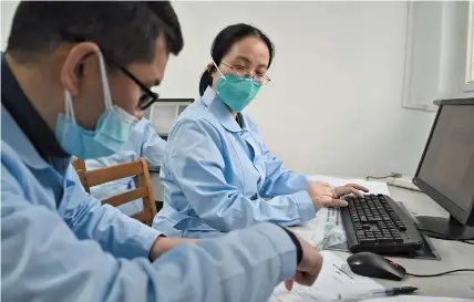  ??  ?? Left: Zha Qiongfang (center), a doctor from Shanghai, consults with a colleague about a report at Wuhan Jinyintan Hospital. Below: Zha and other local doctors who have volunteere­d to help in Wuhan discuss treatment for coronaviru­srelated pneumonia. — Ti Gong
