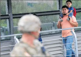  ?? JOHN MOORE/GETTY ?? People pass U.S. Army soldiers while crossing from Mexico into the United States at the internatio­nal bridge Friday in Hidalgo, Texas. President Donald Trump ordered the troops to the border to bolster security at points of entry where an immigrant caravan may cross.