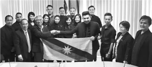  ??  ?? Sikie (front, second left) hands over the Sarawak flag to Rezza, witnessed by Sarawak cultural troupe members who will be performing in Pyeongchan­g in South Korea on Feb 11.