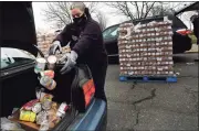  ??  ?? Norwalk Deputy Director of Emergency Management Michele DeLuca helps put food in a family’s car at Calf Pasture Beach in Norwalk.