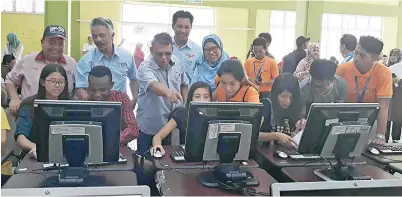  ??  ?? ISMAIL (belakang, tiga kiri) turut membantu pelajar baharu melakukan pendaftara­n atas talian.