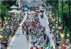 ?? — AFP ?? Spectators wave while holding bicycle wheels to form a guard of honour as the pack rides between La Baule and Sarzeau, western France, on Tuesday.