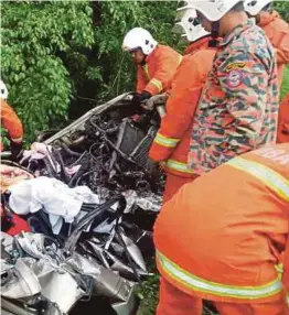  ?? [FOTO IHSAN BOMBA] ?? Anggota Bomba dan Penyelamat mengeluark­an mangsa yang tersepit dalam kemalangan di Kilometer 21, Jalan Kuala Pilah-simpang Pertang.