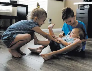  ?? Caroline Brehman ?? Las Vegas Review-journalAbo­ve: Lylah Matheson, 4, left, and Ryder Matheson, 8, tickle their younger brother, Wyatt Matheson, 1, in their Las Vegas home Sunday. Markie Coffer, left, and Travis Matheson with their son Wyatt. Coffer and her husband attended the Route 91 Harvest festival when the shooting happened. The couple made it to safety and Wyatt was born two days later.