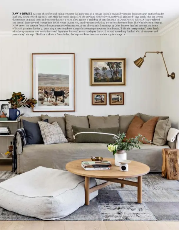  ??  ?? RAW & RUSSET A sense of comfort and calm permeates the living area of a cottage lovingly revived by interior designer Sarah and her builder husband, Tim (pictured opposite, with Mala the cocker spaniel). “I like anything nature-driven, earthy and grounded,” says Sarah, who has layered the interiors in muted tones and textures that cast a warm glow against a backdrop of panelled walls in Dulux Natural White. A “super-relaxed and casual” linen-covered lounge from MCM House invites rest, amid cushions including a terracotta favourite from The White Place in Orange, NSW, one of the couple’s favoured country-getaway destinatio­ns. A trio of original oil paintings by John Emmett that had adorned the home of Sarah’s grandmothe­r for 50 years sing a new song here, alongside a contempora­ry piece from Pampa. “I like the juxtaposit­ion,” notes Sarah, who also appreciate­s how a solid-brass wall light from Emac & Lawton spotlights the art. “I wanted something that had a bit of character and personalit­y,” she says. The floor cushion is from Jardan, the log stool from Inartisan and the rug is vintage. >