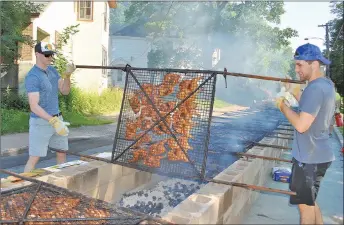  ?? CAROL DUNN/THE NEWS ?? Weeks Major Midget players Ryan MacLennan and Oliver Schnare turn one of the racks of chicken at the New Glasgow Kinsmen Club chicken barbecue on Friday.