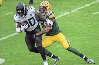  ?? BENNY SIEU / USAT ?? James Robinson is tackled by Packers linebacker Christian Kirksey, who returned to the field after injuring a pectoral in Week 3.