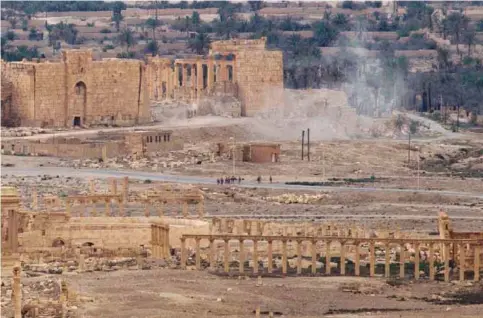  ??  ?? PALMYRA: In this file photo, Russian soldiers stand on a road as smoke rises from a controlled land mine detonation by Russian experts inside the ancient town of Palmyra, Syria in the central Homs province. —AP