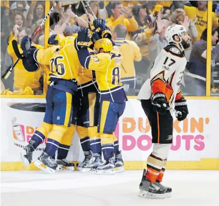  ?? MARK HUMPHREY/THE ASSOCIATED PRESS ?? Anaheim Ducks centre Ryan Kesler skates past as Nashville Predators players celebrate an empty-net goal during the third period of Game 6 of the Western Conference final Monday in Nashville, Tenn. The Predators won the series and will advance.