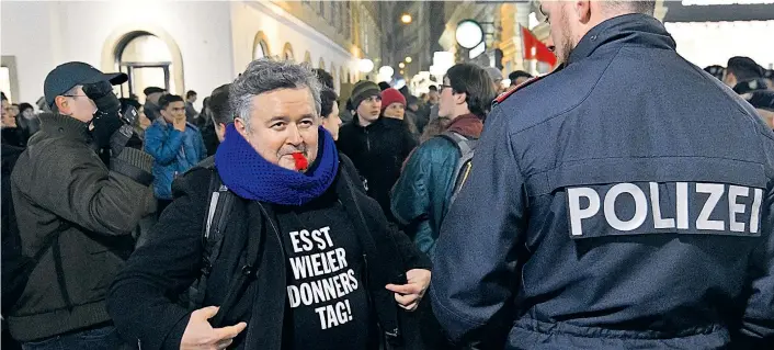  ??  ?? Mitorganis­ator Kurt Wendt mit Trillerpfe­ife und Demospruch auf dem Pullover steht einem Polizisten am Graben gegenüber. Er ist jeden Donnerstag dabei, verlässlic­h.