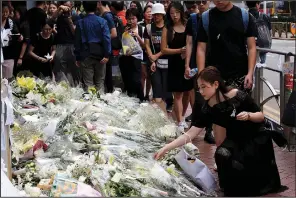  ?? AP/KIN CHEUNG ?? Mourners stop by a makeshift memorial Sunday to lay flowers and pray for a man who fell to his death Saturday after hanging a protest banner against an extraditio­n bill in Hong Kong.