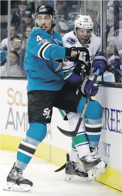  ?? — THE ASSOCIATED PRESS ?? Vancouver’s Thomas Vanek is pushed against the boards by San Jose’s Brenden Dillon during the first period of Saturday’s game in San Jose.