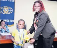  ??  ?? President, Paulette Kirkland, hands the winner’s trophy to Dominic Goldson of Lalyce Gray Basic School.