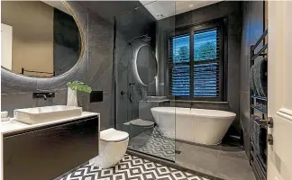  ??  ?? Black shutters by Brightshin­e enhance the drama of this dark, monochroma­tic bathroom.