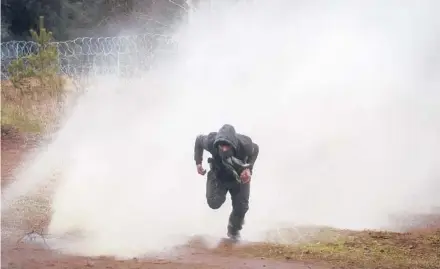 ?? LEONID SHCHEGLOV/BELTA ?? A man tries to evade a water cannon blast during clashes on Tuesday near Grodno, Belarus.
