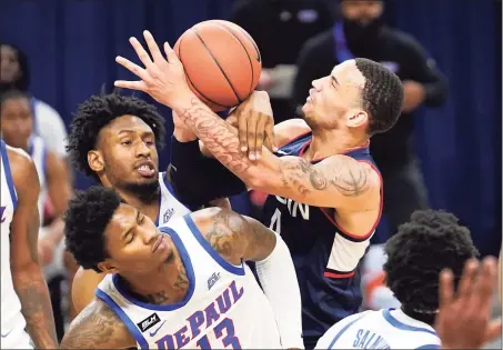  ?? Charles Rex Arbogast / Associated Press ?? UConn’s Tyrese Martin, right, battles DePaul’s Pauly Paulicap and Darious Hall (13) for the ball during Monday’s game.