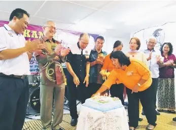  ??  ?? Riot (second left) and Cr Edward Sayu (left) join their hosts at the lighting of the anniversar­y cake. Seen at second and third right respective­ly are Penghulu Roland and PPWS Serian chairman Wendy Peter.