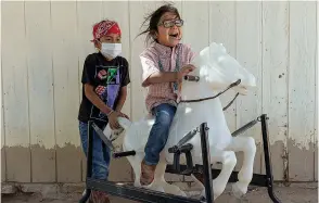  ?? ?? Hataałii Tiisyatoni­i "HT" Begay, 5, rides a toy horse next to his brother Hastiin, 7, at the family ranch on the Navajo Nation. Adriana Zehbrauska­s for The Washington Post