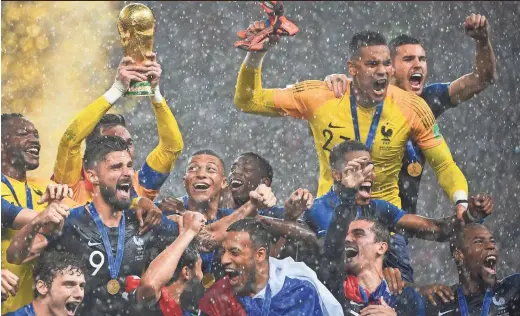  ?? AFP/GETTY IMAGES ?? France's players hoist the World Cup trophy in the rain after winning the title match in Moscow on Sunday.