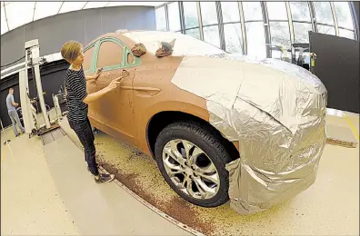  ?? AP/JOSE JUAREZ ?? General Motors creative clay sculptor Gianna Ball smooths loose clay on a model of a 2018 Buick Enclave frame late last month at the GM Tech Center in Warren, Mich.