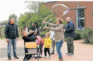  ?? FOTO: OLAF OSTERMANN ?? Der sechsjähri­ge Neo hat beim Schulfest eine Riesenseif­enblase gemacht. Fachlehrer­in Andrea Laermann hilt ihm dabei.