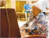  ??  ?? Peggy Rhodes plays the piano during the Let’s Sing From Memory event.