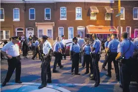  ?? MATT ROURKE/ASSOCIATED PRESS ?? Police officers gather near the scene in Philadelph­ia where six officers were wounded in a standoff with a gunman while serving a drug warrant.