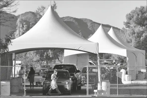  ?? ASOCIATED PRESS ?? IN THIS JULY 28 FILE PHOTO, people wait in line to be tested for COVID-19 at Cesar Chavez City Park in Phoenix. Arizona hospital officials urged people to avoid large Thanksgivi­ng dinners as soaring coronaviru­s infections put pressure on the state’s medical system. Banner Health forecasts it will hit 125 percent of its licensed capacity around Dec. 4.