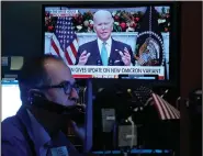  ?? (AP/Richard Drew) ?? President Joe Biden appears on a screen Monday as trader Mark Puetzer works on the floor of the New York Stock Exchange. President Biden urged Americans to get vaccinated including booster shots as he sought to quell concerns Monday over the new covid-19 variant omicron.