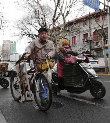  ??  ?? (Left photos) Ma working in an old building in Shanghai. (Above) Ma Jiale pushing his bicycle between jobs in Shanghai.