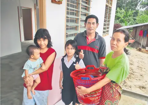  ??  ?? Mazlan and his wife Elisa (right) and their three children Mechellina, seen holding her baby sister Delina, and Adelina starting to move their belongings to their newly completed house.