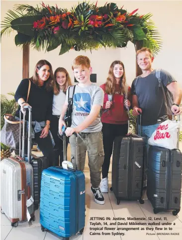  ??  ?? JETTING IN: Justine, Mackenzie, 12, Levi, 11, Taylah, 14, and David Mikkelsen walked under a tropical flower arrangemen­t as they flew in to Cairns from Sydney. Picture: BRENDAN RADKE