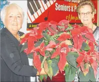  ??  ?? Janice Stagg Harris presents Minnie Piercey with a poinsettia at the Historical Society’s Christmas party.