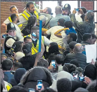  ??  ?? Police battle to hold back an angry crowd on the steps of Kensington town hall yesterday