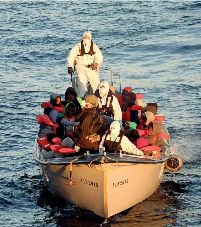  ??  ?? In alto mare Soccorrito­ri della nave italiana Aliseo portano in salvo alcuni dei 290 migranti recuperati al largo della Libia (Afp)