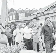  ?? — Gambar Bernama ?? MENINJAU: Dr Mahathir yang juga Anggota Parlimen Langkawi meninjau keadaan kediaman yang musnah dilanda ribut di Kampung Kuala Melaka, Langkawi, semalam.