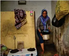  ?? ?? JAKARTA: Bajaj driver and single mother Ekawati, who plies her three-wheeled taxi in a profession overwhelmi­ngly dominated by men comforts her three-year-old daughter Debi after she threw up while on their rounds. (Right) Ekawati washes dishes at her small rented home in Jakarta.— AFP Photos