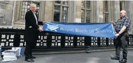  ??  ?? Minnows fight back: Protesters hold a banner outside the Royal Courts of Justice in London on Monday as Royal Bank of Scotland pursues settlement talks with a group of investors.