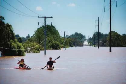  ?? — AFP ?? NORTH MACLEAN: Kayakers paddle on the flooded Logan River, caused by Cyclone Debbie, as it flows over the Mt Lindesay Highway in Waterford West near Brisbane.