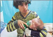  ?? (AFP) ?? A Syrian boy holds an oxygen mask over the face of an infant at a makeshift hospital following a reported gas attack on the rebel-held besieged town of Douma in the eastern Ghouta region on the outskirts of the capital Damascus on Jan 22. At least 21...