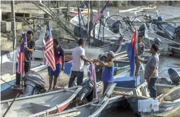  ??  ?? Orang Asli in Kampung Baru, Kuala Benut decorating their boats with the national flag. — Bernama photo