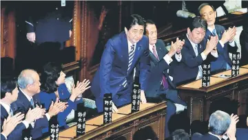  ??  ?? Abe (centre) stands as he is re-elected as prime minister while his party lawmakers clap their hands at the Lower House of Parliament in Tokyo, Japan. — Reuters photo